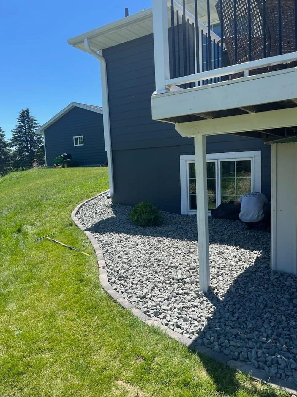 Gravel landscaping along a home's foundation with a clear blue sky in the background.