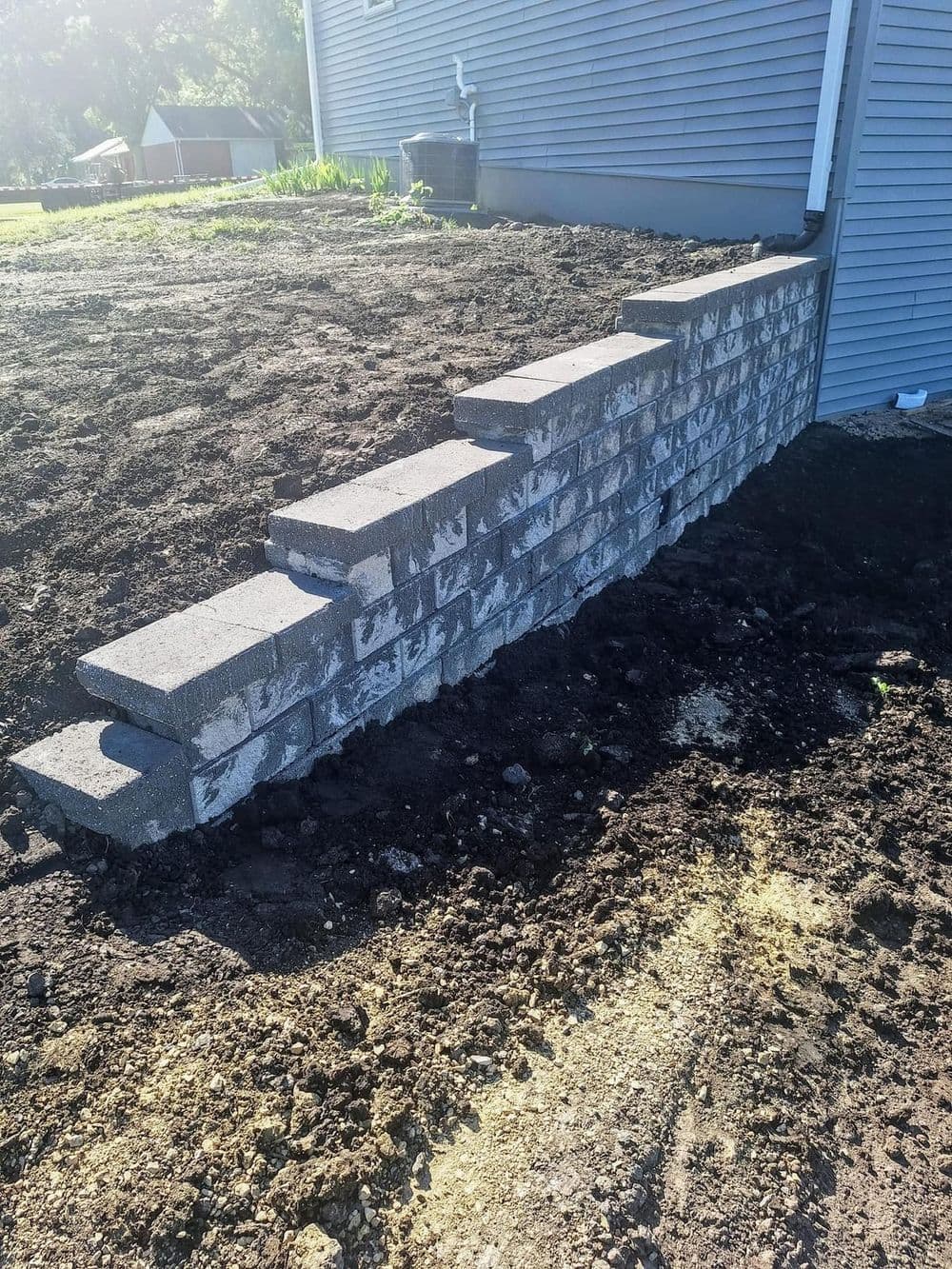 Concrete block steps leading up to a house, surrounded by freshly tilled soil.